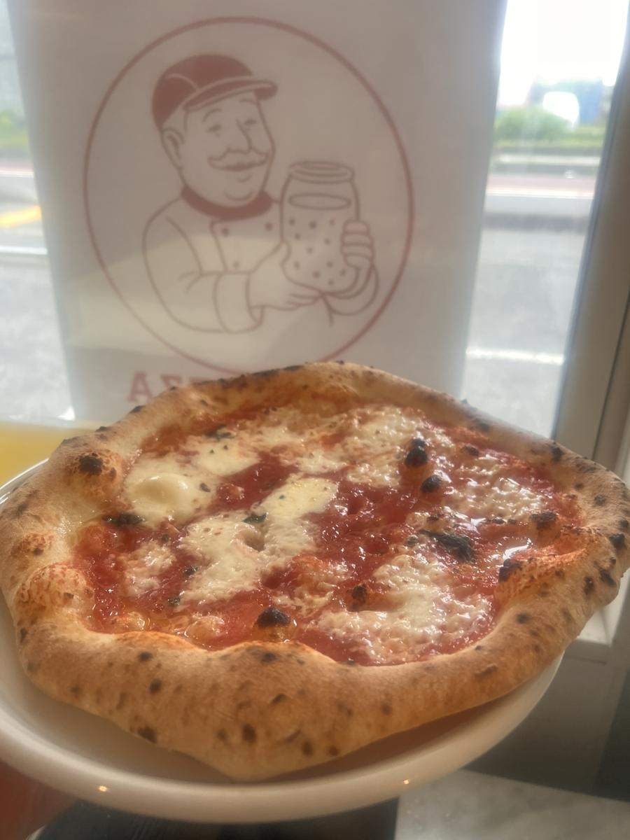 窓に貼った店のロゴの前で撮ったマルゲリータ
